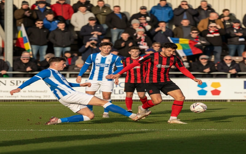 Nailsea and Tickenham players in action during home fixture with supporters in background
